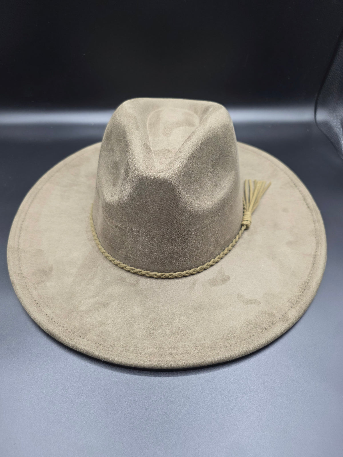 Beige cowboy hat with a gold band on a dark background