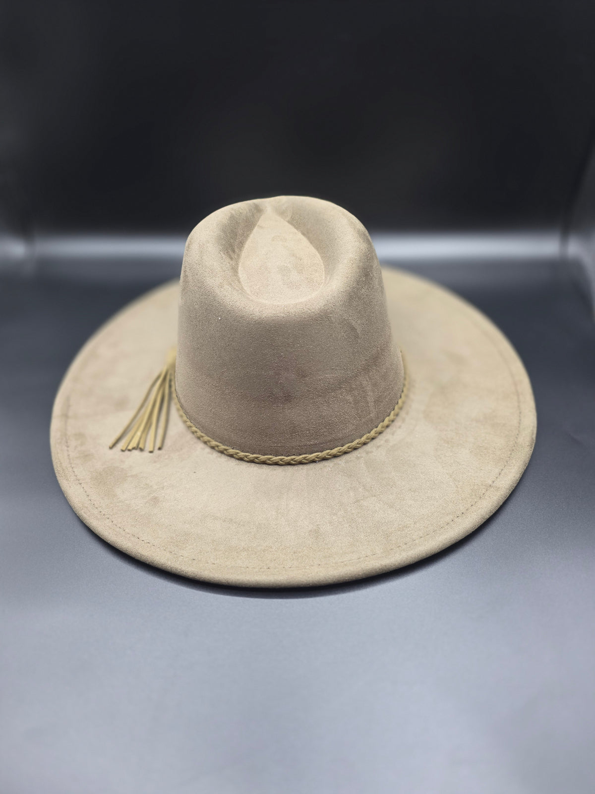 Beige hat with a decorative tassel on a metallic surface